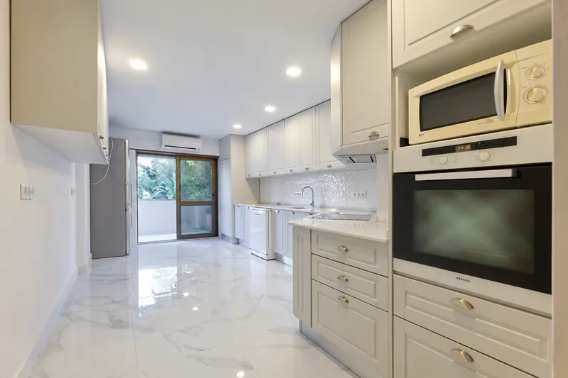 Cozinha renovada, com armários ao longo das duas paredes e pavimento em porcelânico